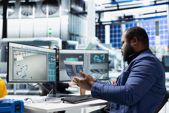 Black building contractor reviews solar tech systems on files and pc, supporting assembly and production line. Modern energy systems with sustainable solutions for green technology.
