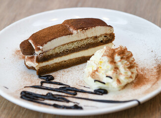 Tiramisu cake with whipped cream on a white plate.