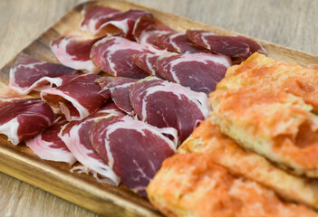 Slices of prosciutto crudo on a wooden plate