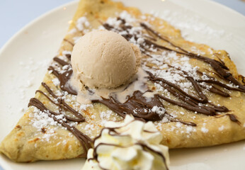 Pancakes with ice cream and chocolate sauce on a white plate