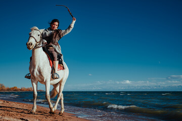 Young asian woman ride on horse on lake shore on summer day