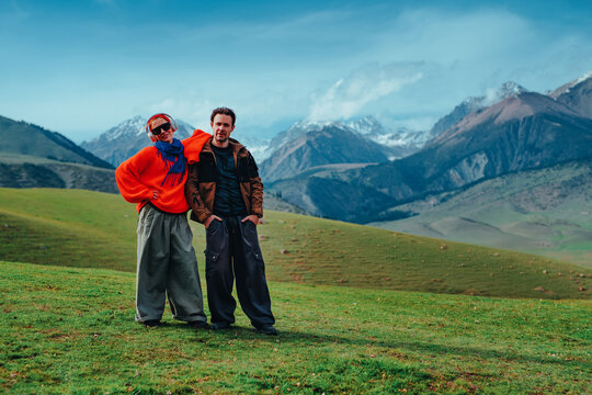 Man and woman tourists standing in the mountains on green meadow