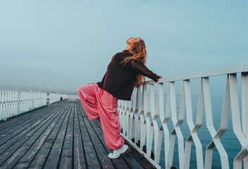 Young beautiful woman posing on pier on lake shore