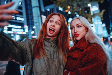 Two young women making selfie on night Seoul street, emotional portrait