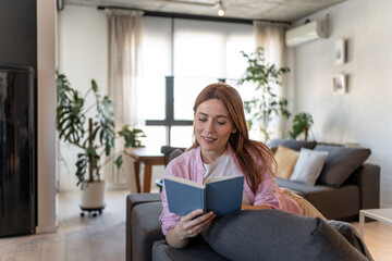 Woman reading a book while relaxing on sofa at home