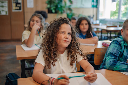 Curious girl winking and thinking during class at elementary school - Powered by Adobe