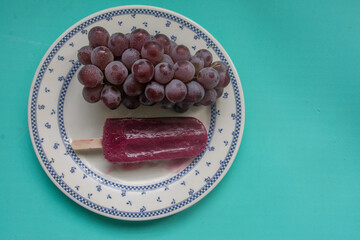 Grape popsicles , grapes and purple flowers on a green background. Selective focus.