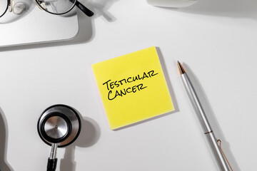 The phrase “Testicular Cancer” is shown on a notepad, placed amid clinical instruments on a...