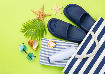 Blue beach bag with summer accessories on color background, top view