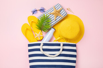 Blue beach bag with summer accessories on color background, top view