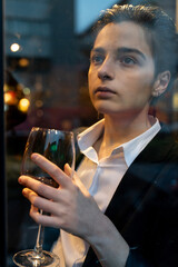 Young woman holding a wine glass in front of the window