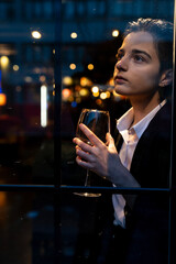 Young woman holding a wine glass in front of the window