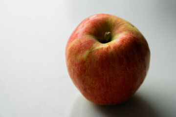 A close-up image of a fresh red and green apple with a smooth surface on a white background.