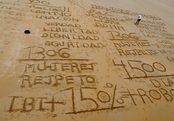 Mensch malt Wörter in den Sand