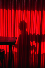 silhouette of a mysterious woman behind a red curtain