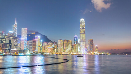 Fototapeta premium Hong Kong, China skyline panorama with skyscrapers day to night from across Victoria Harbor timelapse.