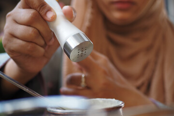 Woman seasoning food with salt at a casual dining setting