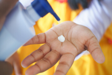 Child Applying lotion to hand before event in colorful attire