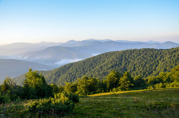 Misty mountains and forested hills during an early morning surrounded by serene greenery in...