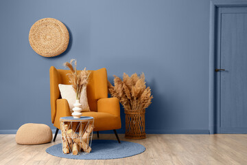 Armchair, coffee table and pampas grass in interior of living room