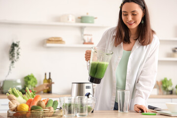 Young woman with blender of vegetable juice in kitchen