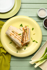 Plates of tasty shawarma with onion on green wooden background