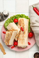 Plate of tasty shawarma with lettuce and tomatoes on white tile table