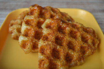 close up of waffle croissants on a yellow plate on a wooden table