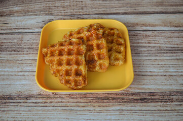 close up of waffle croissants on a yellow plate on a wooden table