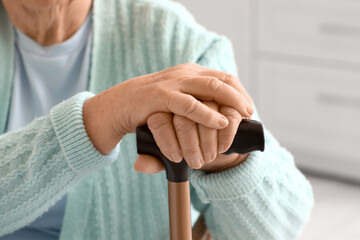 Senior woman with walking stick at home, closeup