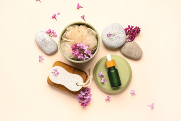 Foot file with bottle of cosmetic oil, loofah and lilac flowers on beige background