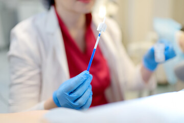 Gynecologist examines a patient takes a smear from a woman cervix. Close up view of doctor hands with gynecological cytobrush. Diagnosis of female viral and infection diseases.