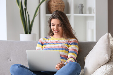 Female freelancer working with laptop on sofa at home