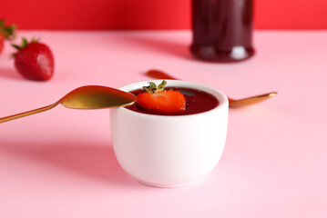 Bowl of sweet strawberry jam on color background