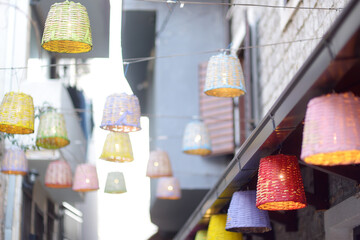 Decorative multicolor wicker lamps are hanging under the street in a small European town