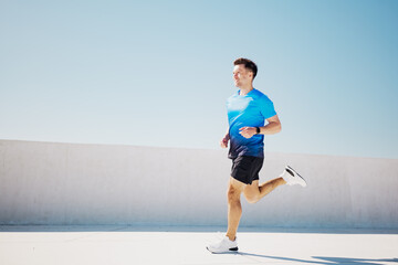 Running in the bright sunlight, a man enjoys his workout on an open rooftop in a vibrant cityscape