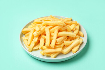 Plate with golden french fries on turquoise background, closeup