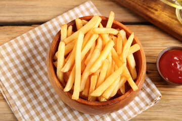 Bowl with tasty french fries and bowl of ketchup on brown wooden background