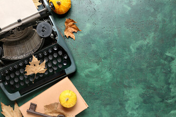 Vintage typewriter, pumpkins, book and autumn leaves on green background