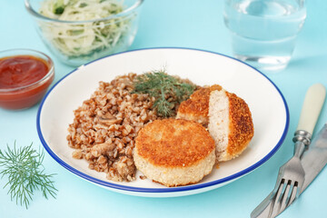 Plate of tasty meat cutlets with buckwheat on blue background