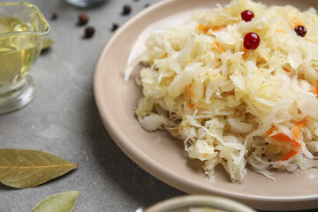 Plate with delicious sauerkraut and different spices on grey background