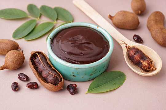 Bowl with tasty tamarind jam with fruits on beige background