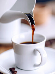 Freshly brewed espresso is poured into a small white cup, creating a inviting scene for coffee lovers.