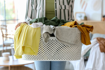 Young woman with basket full of dirty clothes at home, closeup