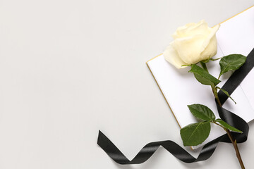 Rose with black ribbon and blank open notebook on white background