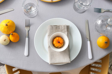 Autumn table setting with pumpkins, cutlery and clean plates