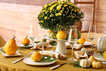Autumn table setting with flowers and pumpkins in dining room