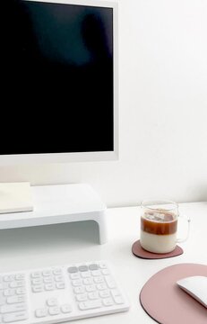 Minimalist workspace with coffee and white computer setup on clean white desk
