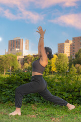 African American woman outdoors in yoga pose with cityscape in background. 