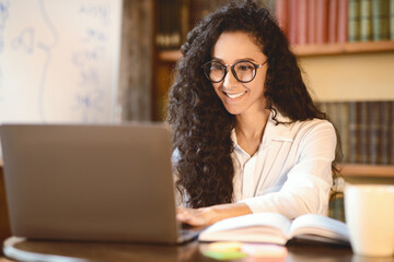 Freelance Concept. Portrait of smiling woman in eyeglasses using and working on computer, typing on...